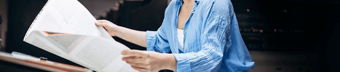 woman looking for printing irregularities on paper from a recent print job