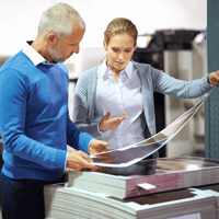 Man and woman looking at paper that was recently printing on.