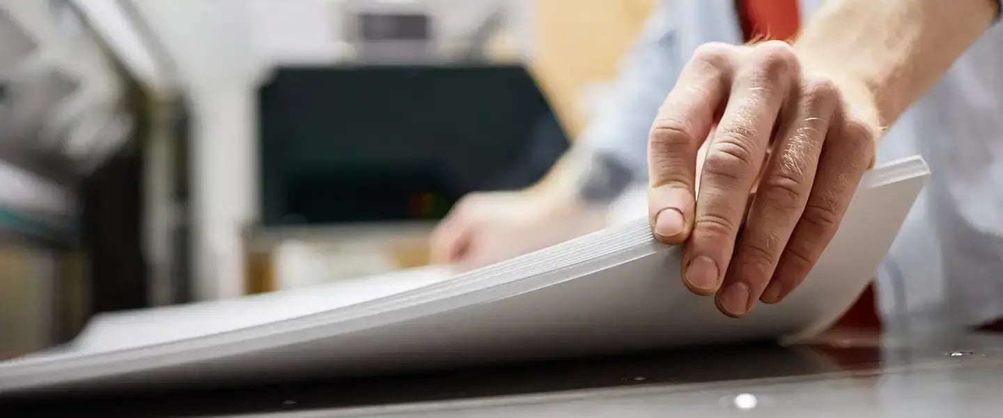 A hand holding a stack of paper